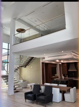 Floating stair and glass-railed loft above a dining and lounge area with modern pendants