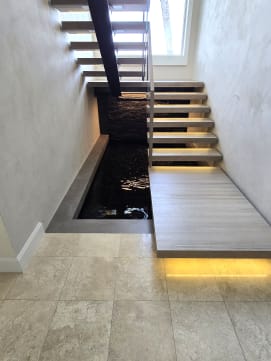 Floating stair with a large LED-lit lower landing extending over an indoor reflecting pool