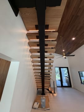 Long black mono stringer with LED-lit oak treads under a walnut ceiling