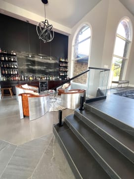 Frameless glass on black talon spigots edges steps down to a sunken bar lounge with arched windows