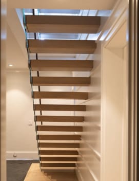 Straight run of white oak cantilever treads with frameless glass in a paneled stairwell