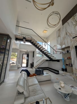 Black FLIGHT Mono floating stair with frameless glass rising through a double-height room with marble walls
