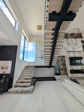 White oak FLIGHT Mono switchback starting from a marble plinth with frameless glass and black handrail