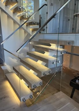 White mono stringer with light oak LED-lit floating treads and frameless glass on stainless standoff pins.