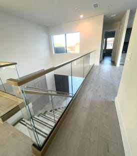 Frameless glass in a champagne-finish base rail with matching cap along an upstairs hallway