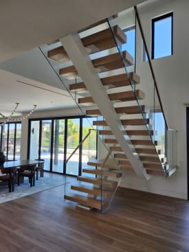White center stringer and white oak treads with frameless glass and oak handrail over a dining room