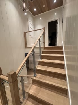 Straight oak stair with aluminum-post glass railing and oak handrail under a wood ceiling