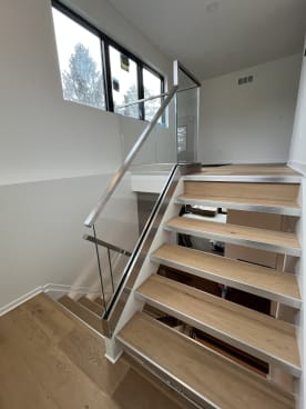 Oak treads on brushed stainless stringers with frameless glass and stainless handrail