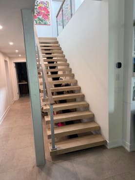 Straight run of light oak floating treads with glass railing along a hallway