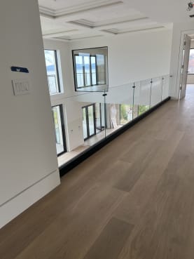 Black base rail glass with a slim top cap runs along an upstairs loft above a double-height room