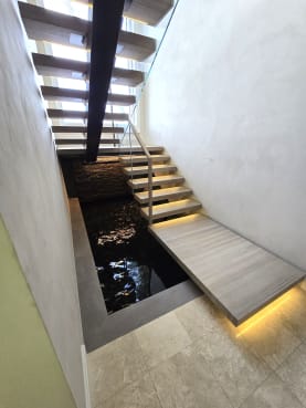 Mono stringer floating stair with a wide LED-lit landing over a reflecting pool
