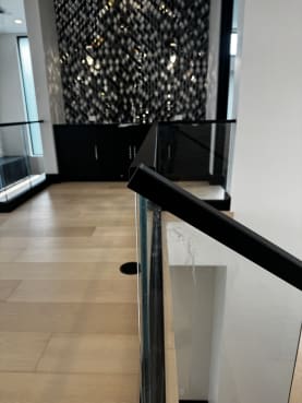 Frameless glass in a black base rail with a black top cap along an upper landing