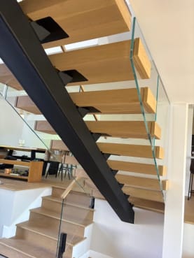 White oak floating treads on a black mono stringer with glass on black ascend talons