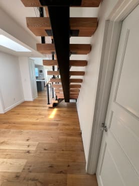 Black mono stringer with thick red oak treads seen from below in a long hallway