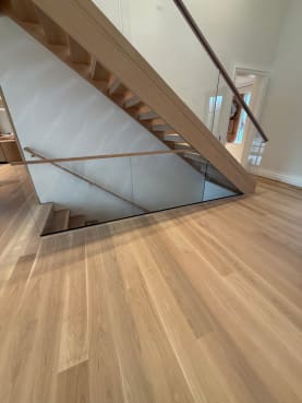 Frameless glass with an oak handrail guards a stair opening on wide white oak floors
