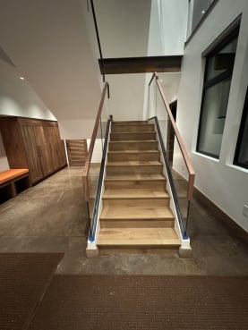 Frameless base rail glass with walnut handrails flanking a wide white oak stair