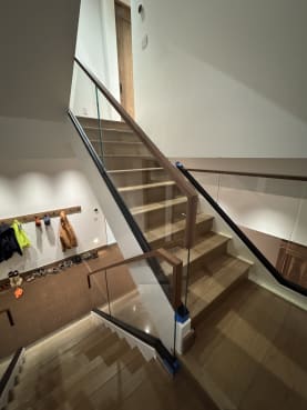 Frameless base rail glass with walnut handrails follows a white oak switchback stair