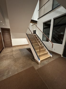 White oak stair with frameless base rail glass and walnut handrails in a mudroom entry