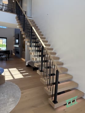 White oak FLIGHT Mono stair with LED-lit treads, decorative black iron balusters and an oak handrail