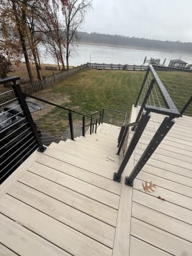 Deck stair with black cable railing toward lake