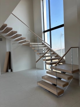 Floating stair with glass railing in a tall window bay