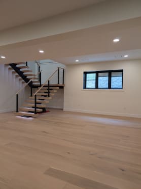 White oak mono switchback stair with cable railing set in a large open room with light oak floors.