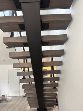 Underside view of a dark mono stringer with charcoal wood floating treads