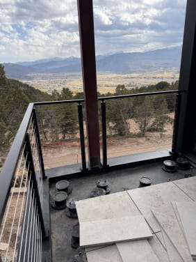 Black cable railing corner on a balcony looking out over a mountain valley