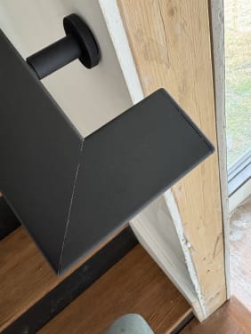 Close view of a black steel handrail return on a round wall bracket