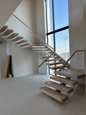 Floating stair with glass railing in a tall window bay