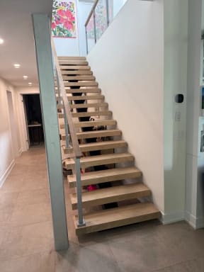 Straight run of light oak floating treads with glass railing along a hallway
