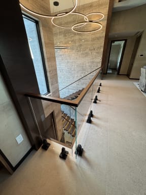 Frameless glass on black surface talons with a walnut handrail along an upstairs stair opening