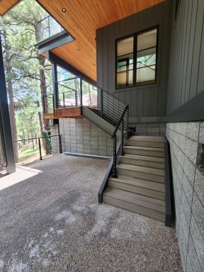 Black cable railing follows composite exterior stairs up to a cantilevered deck