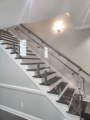 Stainless post-mounted glass railing with a round stainless handrail along a dark-tread commercial stair