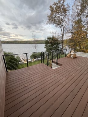 Composite deck with black cable railing overlooking a lake framed by fall foliage
