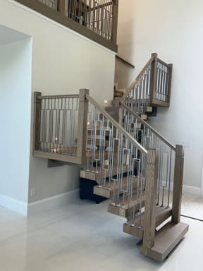 Oak treads on a mono stringer turn at a landing with wood newels and geometric metal balusters.
