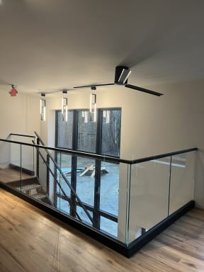 Glass railing in a black base rail meets cable railing on the adjoining stair beneath modern pendant lights.