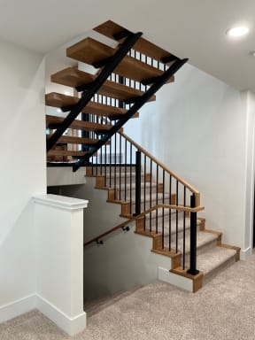 Hickory treads on a black steel stringer with black iron balusters and a hickory handrail turning down to a landing.