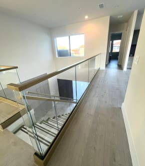 Frameless glass in a champagne-finish base rail with matching cap along an upstairs hallway