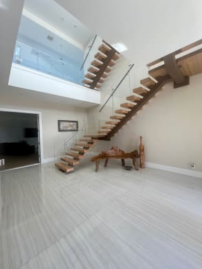 Wood floating treads on a wood-clad mono stringer climb past glass railing to a glass-railed loft.