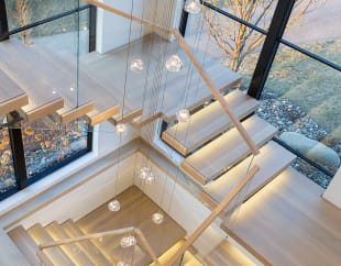 Overhead view of light oak cantilever treads and glass railing with LED lighting beneath glass globe pendants.