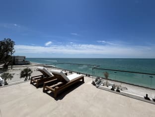 Frameless talon glass with a black cap lines a rooftop deck with loungers facing the turquoise sea