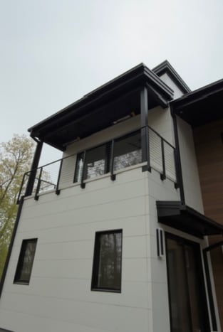 Black rod railing on a covered upper balcony of a white modern home