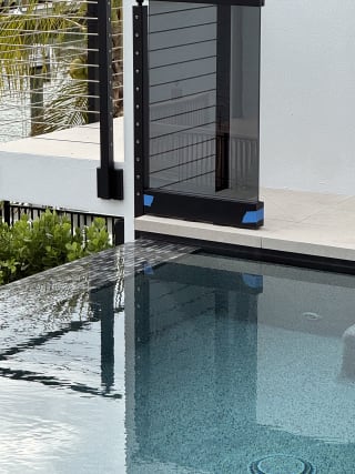 Solar gray glass and cable railing at the edge of an infinity pool