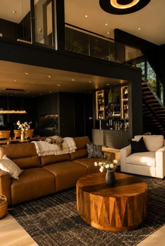 A black FLIGHT Mono with glass railing rises behind a leather sofa in a moody dark-walled great room.