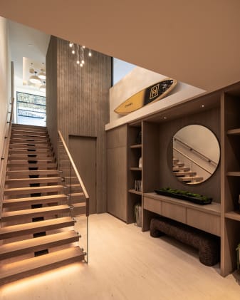 Light oak FLIGHT floating stair with LED-lit treads and frameless glass in a base rail rising through a wood-paneled entry.