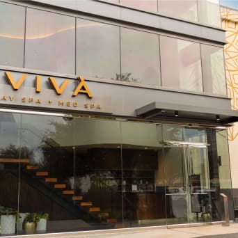 A wood floating stair is visible through the glass facade of a commercial spa storefront.