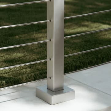 Close view of a silver aluminum post with base cover and stainless horizontal rods above a lawn.