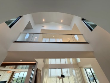 Black base rail glass with a wood cap lines a bright loft framed by a sweeping arched ceiling