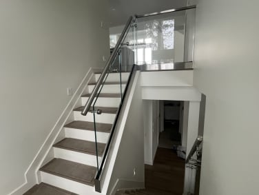 Frameless glass in a stainless base rail with a round stainless handrail along a split-level stair